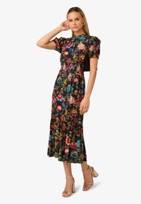 Zwarte bloemenjurk met pofmouwen, gerimpelde zoom en elastische taille. Heeft kleurrijke bloemenpatronen tegen een donkere achtergrond.