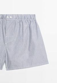 Boxer a righe in blu e bianco, con fascia elastica in vita, due bottoni frontali e una piccola tasca con cuciture bianche.