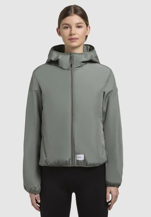 Veste à capuche vert clair avec une fermeture éclair complète, des poignets élastiques et une taille élastique. Fabriquée en matériau léger et lisse. Comprend une étiquette au bas.