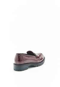 Mocasines de charol burdeos con suela de goma negra baja, punta redondeada y detalles de costura a lo largo del empeine y los lados.