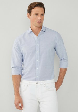 Lichtblauw gestreept shirt met een button-down kraag, opgerolde mouwen en witte knopen, gecombineerd met witte broek. Glad stofgevoel.
