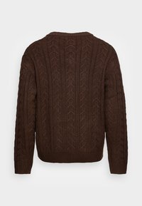 Pull marron tricoté avec un motif torsadé texturé, col rond, poignets et ourlet côtelés. La vue de dos met en valeur le motif complexe.