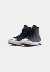 Adidași înalți din piele bleu închis cu accente gri. Prezintă o talpă din cauciuc alb, căptușeală din plasă și un design clasic al vârfului.