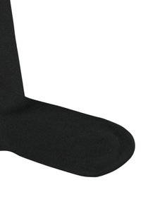 Calza nera in cotone con una texture liscia, caratterizzata da punta rinforzata e polsino a coste per una calzata sicura. Lunghezza simile a quella standard a giro polpaccio.