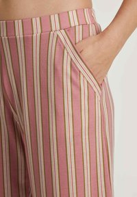 Gestreepte broek in roze, groen en wit. Heeft een brede tailleband en een zijzak. Gemaakt van een gladde, lichte stof.