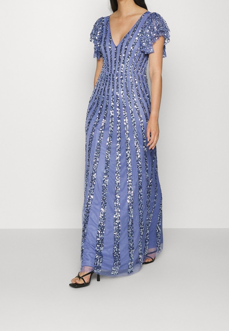 Dlouhé, splývavé večerní šaty v světle modré barvě s hlubokým výstřihem do V, zdobené stříbrnými flitry a volánovými rukávy, tvořící pruhovaný vzor.