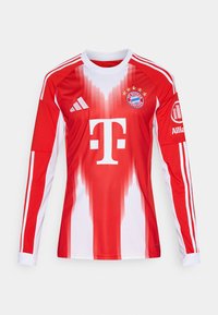 Sarkans un balts futbola krekls ar gariem piedurknēm, kas satur gradientus, kluba logo un trīs svītras uz piedurknēm, izgatavots no elpojoša materiāla.