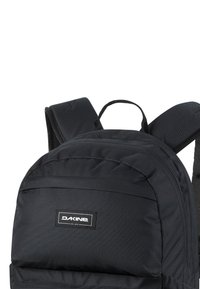 Zwarte stoffen rugzak met gevoerde banden, een handvat aan de bovenkant en een voorvak met rits. Bevat een "DAKINE" logo tag aan de voorkant. Vlotte textuur.