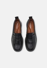 Black loafers made of smooth leather, featuring a rounded toe, a front strap, and small pull tabs at the heel. Brown insole visible.