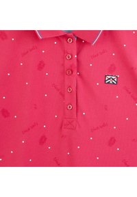 Polo rouge avec des pois blancs et des imprimés de feuilles de palmier, doté d'un col contrasté et d'une fermeture à cinq boutons. Comprend un détail de logo brodé.