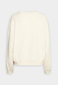 Sweat-shirt à manches longues couleur crème avec col rond et poignets côtelés, présenté de dos sur un fond gris clair uni.