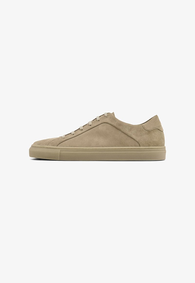 Sneaker beige in suede con punta rotonda, suola piatta in gomma e chiusura con lacci. Superficie liscia e design minimalista con dettagli di cucitura discreti.