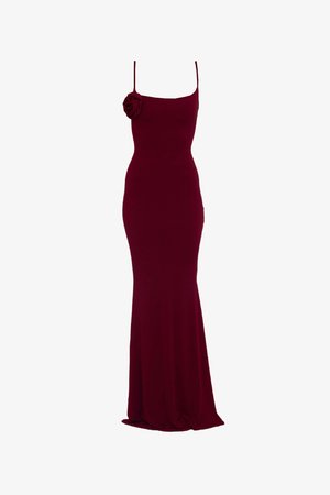 Vestido de noite bordeaux com uma silhueta ajustada, alças finas e um detalhe de rosa em tecido no ombro esquerdo; material liso e elástico.