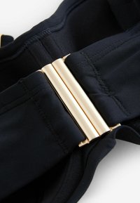 Cintura in tessuto nero con una texture liscia, dotata di una chiusura in hardware dorato al centro. Bordo cucito e design elegante.