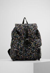 Sac à dos noir à motif floral avec rabat pliant, bretelles réglables et accents en cuir. Comprend plusieurs poches et un tissu texturé.