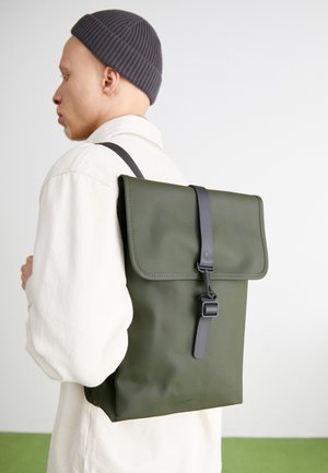 Sac à dos étanche vert avec un dessus rabattu, une sangle grise et une fermeture à boucle. Texture lisse, forme rectangulaire et détail de logo embossé.