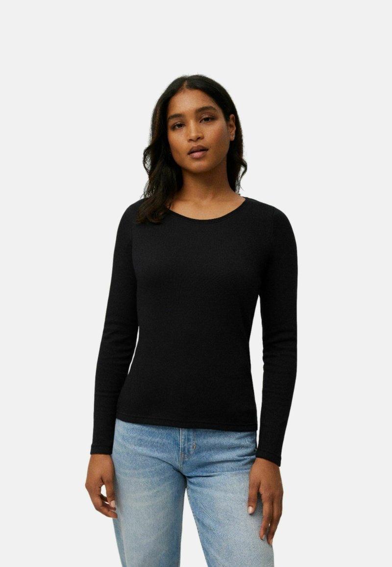 Camisa negra de manga larga con escote redondo, diseño ajustado, textura suave, combinada con jeans de mezclilla azules. Estilo simple y clásico.