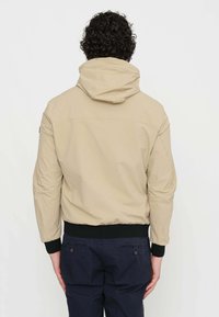 Giacca beige con cappuccio, dotata di polsini e cintura elastici. Realizzata in tessuto liscio, presenta un design semplice senza motivi o loghi visibili.