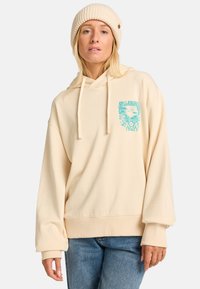 Beige huppari, joka on valmistettu pehmeästä kankaasta ja jossa on etupainatus turquoise-värillä. Siinä on nyörit, ylisuurta kokoa sekä resorit hihansuissa.