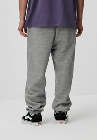 Szare, polarowe spodnie dresowe o luźnym kroju, z elastycznymi mankietami. W połączeniu z czarno-białymi sneakersami Vans. Prosty design, bez wzorów.