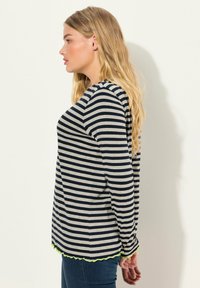 Maglietta a maniche lunghe a righe in tessuto blu navy e grigio chiaro, con un orlo ondulato verde fluo e una vestibilità morbida.