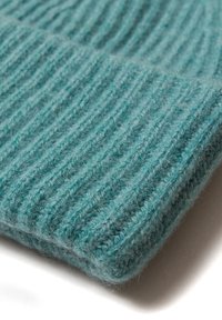 Beanie lavorato a maglia color teal con un motivo a coste testurizzato. Realizzato in morbida lana, presenta un orlo piegato e una finitura leggermente pelosa.