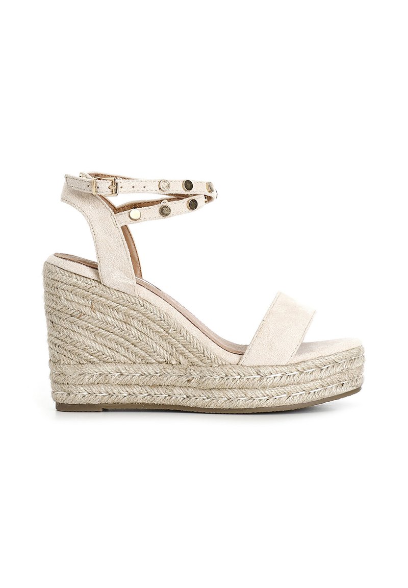 Sandali wedge beige con base in espadrille intrecciata e texturizzata. Presentano una tomaia in suede e una cinghia alla caviglia con borchie metalliche decorative.