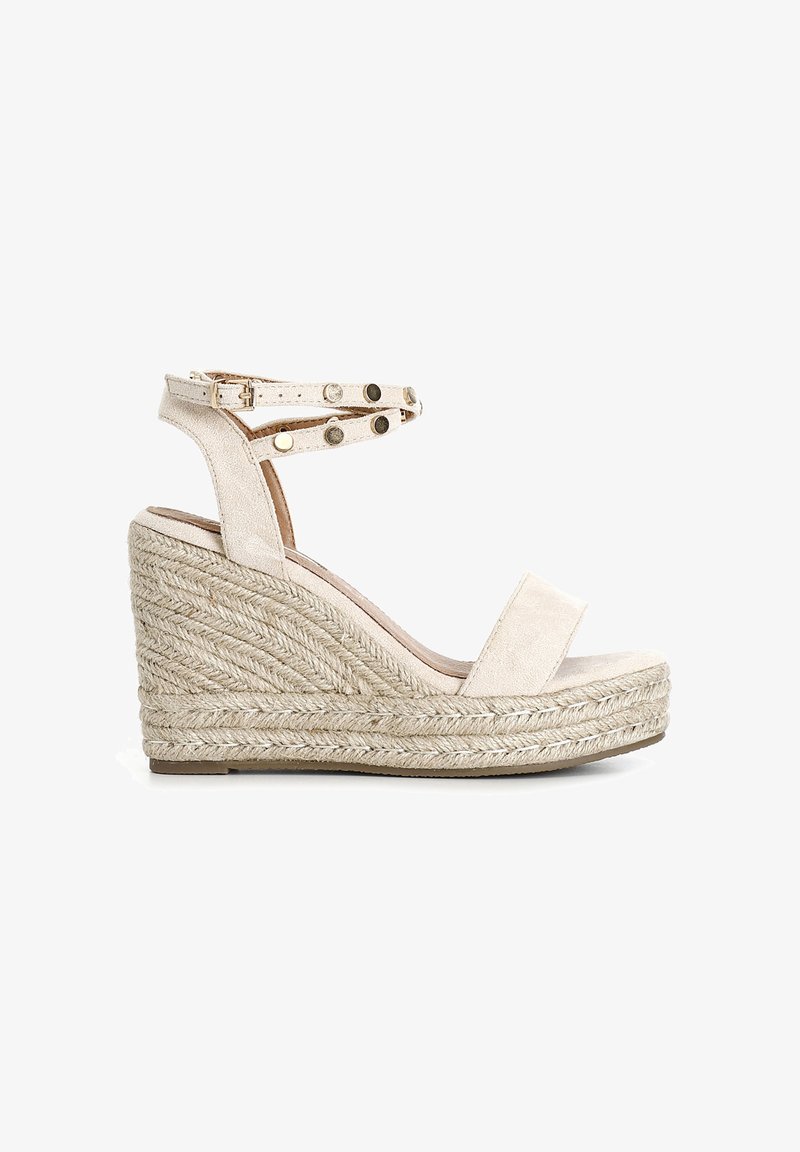 Beige kile sandals med en struktureret, vævet espadrille-base. Har en overdel i ruskind og ankelrem med dekorative metalliske nitter.