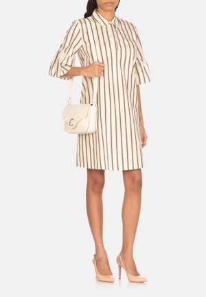 Abito a righe in crema e marrone, maniche corte con polsini svasati, abbinato a una borsa a tracolla bianca con chiusura dorata e tacchi beige.