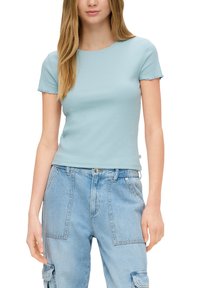Lichtblauw katoenen T-shirt met een ronde halslijn en korte mouwen. Heeft ruwe randafwerkingen. Gecombineerd met lichtblauwe denim cargo-broeken.