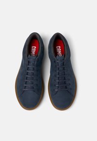 Navyblå mockasneakers med rund tå, gummisula och grå snören. Har en röd innersula med texten "CAMP".