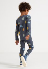 Børns pyjamas sæt i marineblå med farverige tegneserie-lignende figurer. Lange ærmer og leggings lavet af blødt, strækbart bomuldsstof.