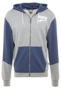 Hoodie zippé gris et marine en mélange de coton, avec une poche kangourou, une capuche avec cordon de serrage et un logo sur la poitrine. Texture douce.