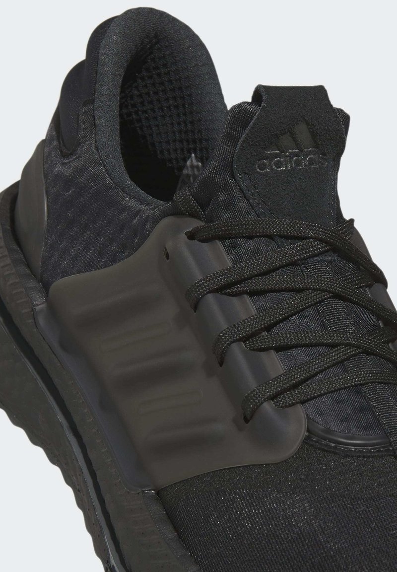 Schwarzer Sportschuh mit strukturiertem Mesh-Obermaterial, Kunststoffüberzügen und flachen Schnürsenkeln. Verfügt über eine gepolsterte Sohle und ein markenmäßiges Accent an der Ferse.
