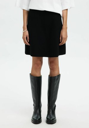 Jupe noire en A en tissu doux, associée à des bottes en cuir noir jusqu'aux genoux, mettant en valeur un design épuré et une texture lisse.
