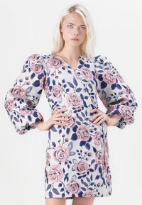 Φλοράλ φόρεμα με σχέδιο τύπου τύλιξης, διαθέτει μεγάλες ροζ και ναυτικές τριαντάφυλλες σε ανοιχτό φόντο, και φουσκωτά μανίκια με λεία υφή.