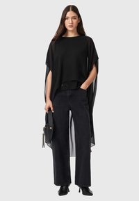 Haut noir léger avec manches transparentes, associé à un jean noir taille haute à jambes larges. Accessoire : un petit sac noir avec une bandoulière.