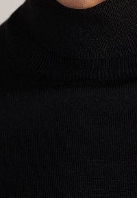 Pull à col roulé noir en tissu côtelé, doté d'un col haut et d'un design sans couture autour du cou. Texture lisse partout.