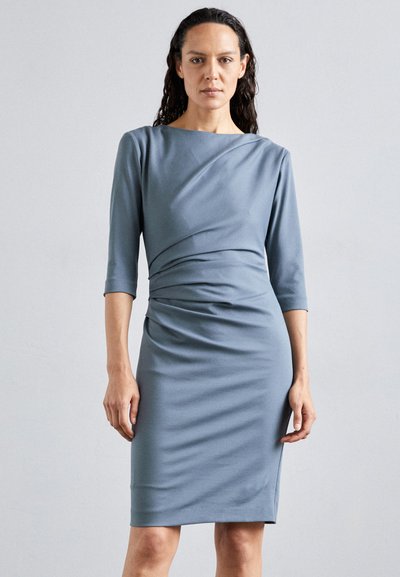 Robe longueur genou en tissu bleu clair doux. Dotée d'un devant drapé, de manches trois-quarts et d'une silhouette près du corps. Texture lisse et design élégant.