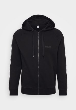 Sudadera con cremallera negra y capucha, con franjas laterales blancas en contraste y el logo de Moschino en el pecho. Fabricada con tejido suave.