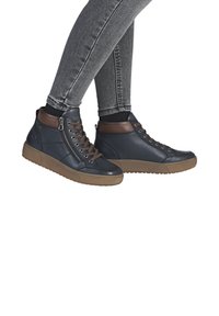 Baskets montantes en cuir bleu marine avec des accents en cuir marron, dotées d'une fermeture éclair sur le côté, d'un laçage à l'avant et d'une semelle en caoutchouc texturé couleur gomme.