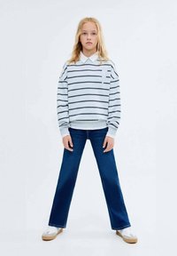 Hanorac gri cu dungi, prevăzut cu guler, asortat cu blugi albaștri. Blugii au un design evazat. Încălțămintea include adidași bej și albaștri.