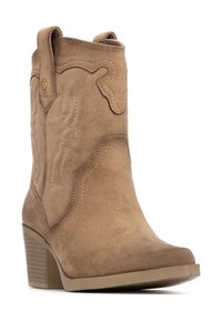 Bota de vaquero de ante marrón con detalles de costura, puntera redondeada y un tacón bajo y modesto. Cuenta con lengüetas para facilitar su uso.