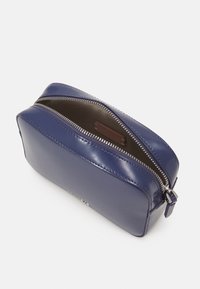 Borsetta in pelle blu navy con finitura lucida, forma rettangolare, zip argentata e un interno scuro con etichetta del marchio.