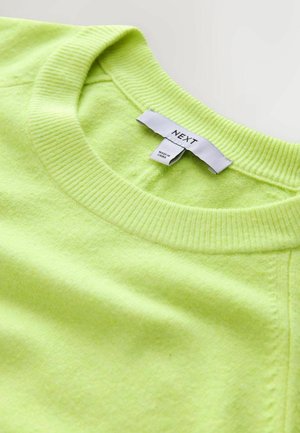 Ljusstark neongrön tröja med ribbad rund halsringning, mjuk textur och en etikett märkt "NEXT." Enkel design med få sömmar.