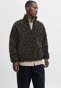 Jas met luipaardprint van fluffy bruin en zwart materiaal. Beschikt over een ritskraag en een relaxte pasvorm, met verlaagde schouders en lange mouwen.