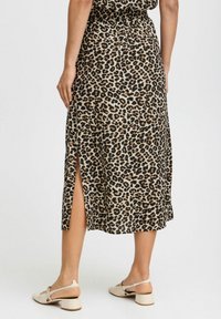 Leopardmönstrad midikjol i lätt material med sidoklipp, har en figurnära midja och ett flödande design. Buren med beige klacksandaler.