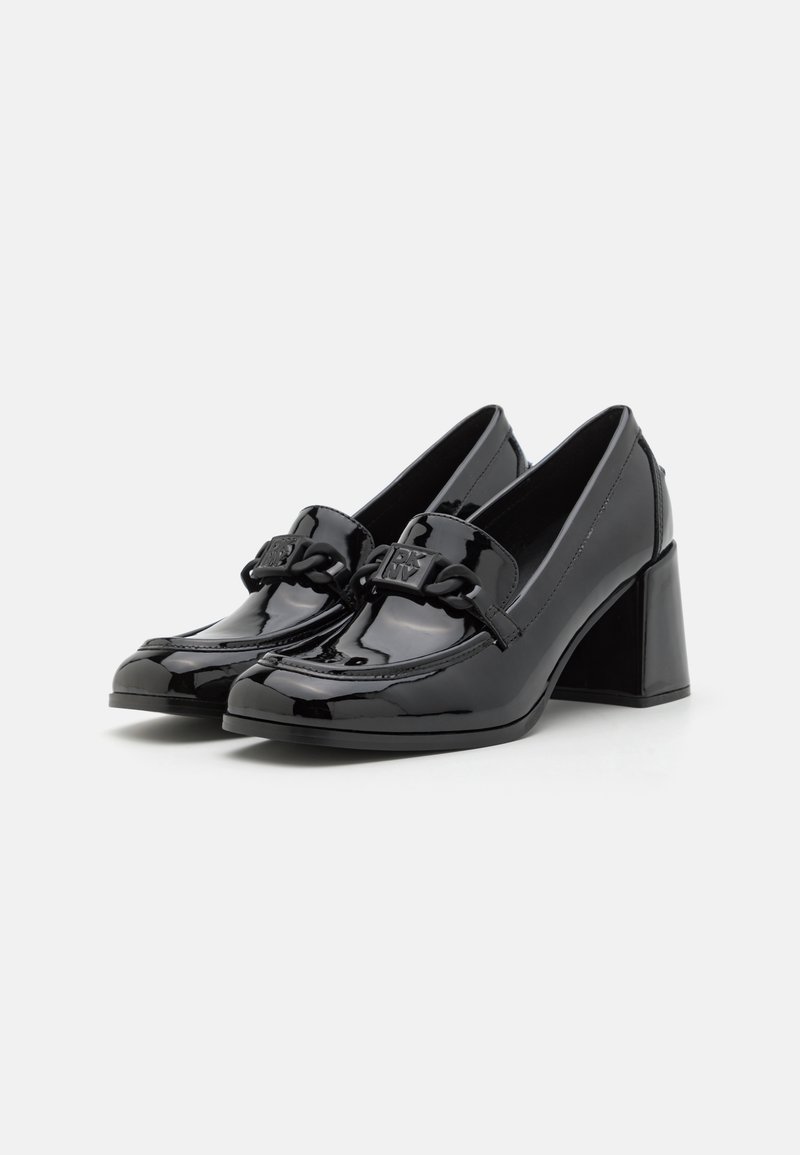 Chaussures en cuir verni noir avec un petit talon bloc, présentant une bandoulière tressée et un matériel de marque à l'avant. Design à bout rond.