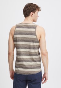 Herreærmeløs tanktop i beige og brune vandrette striber. Lavet af blødt stof med en glat tekstur og rund halsudskæring.