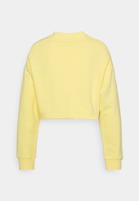 Sweat-shirt jaune court à manches longues, poignets côtelés et col rond. Texture de tissu lisse sans motifs ni éléments visibles.